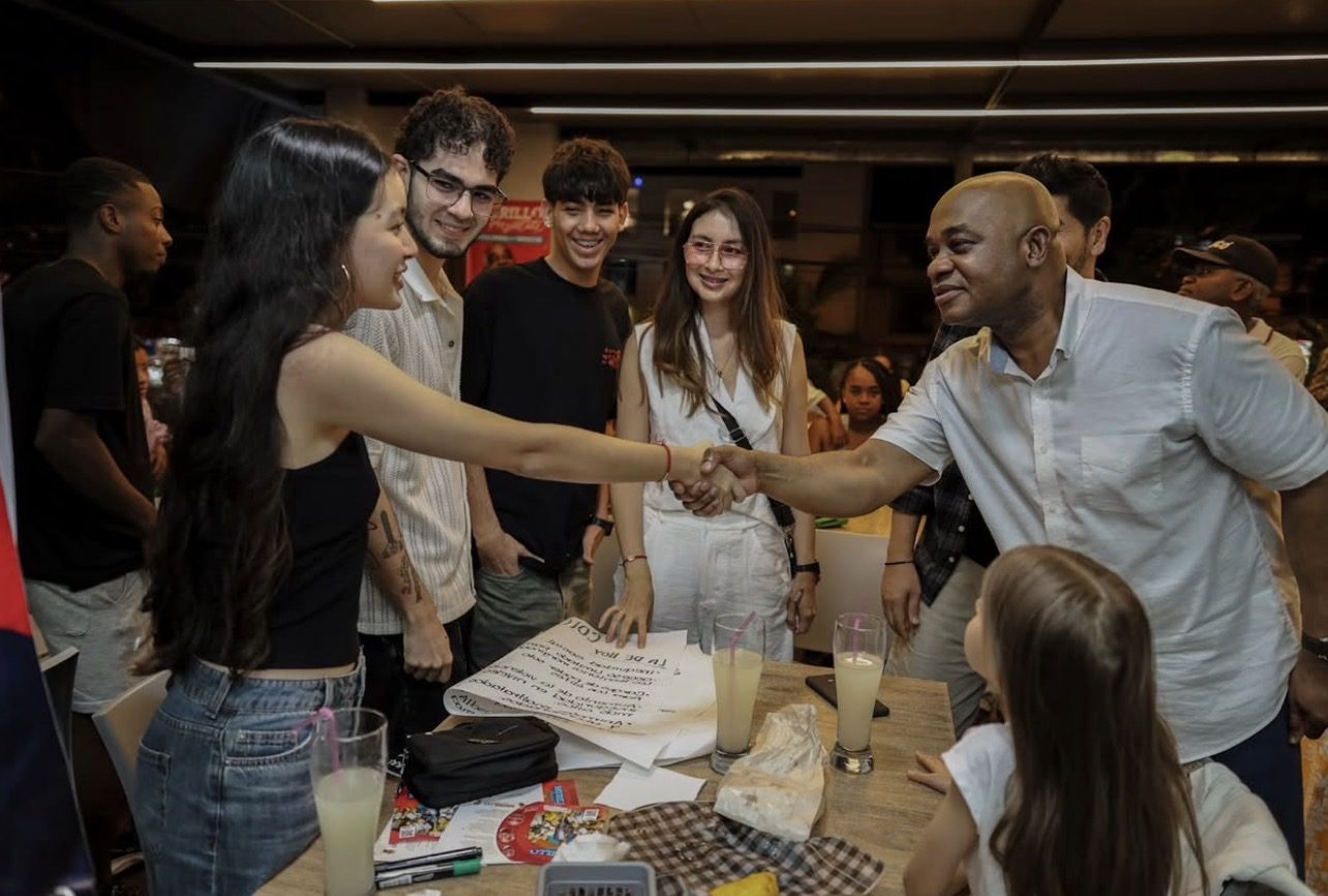 Luis Gilberto Murillo saludando a jóvenes en un evento nocturno